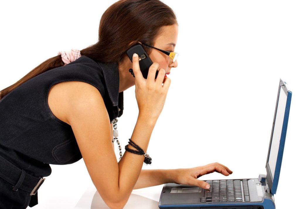 Young Girl Talking On The Telephone And Using A Notebook Computer